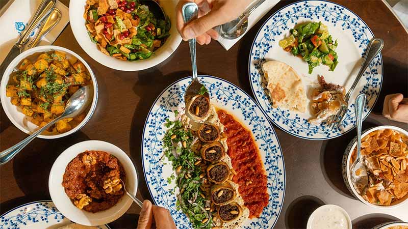 Middle Eastern dining table with grilled kebabs, hummus, salad, flatbread, and assorted traditional dishes
